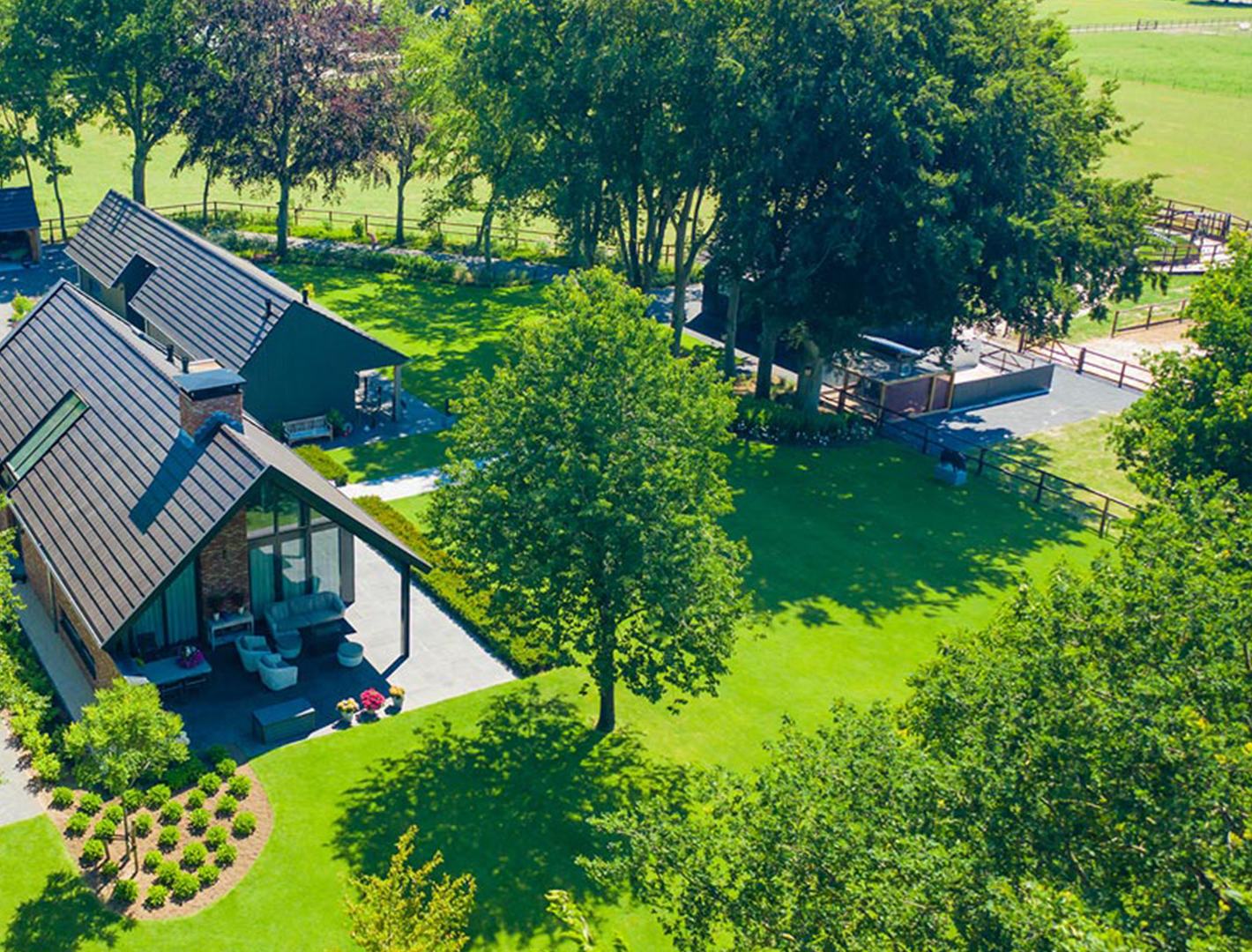 Luchtfoto van een landelijke tuin met gazon, bomen en een overdekt terras